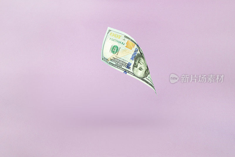 一百美元。One hundred.粉红色粉彩背景下飞扬的美元钞票。投资与储蓄观念。